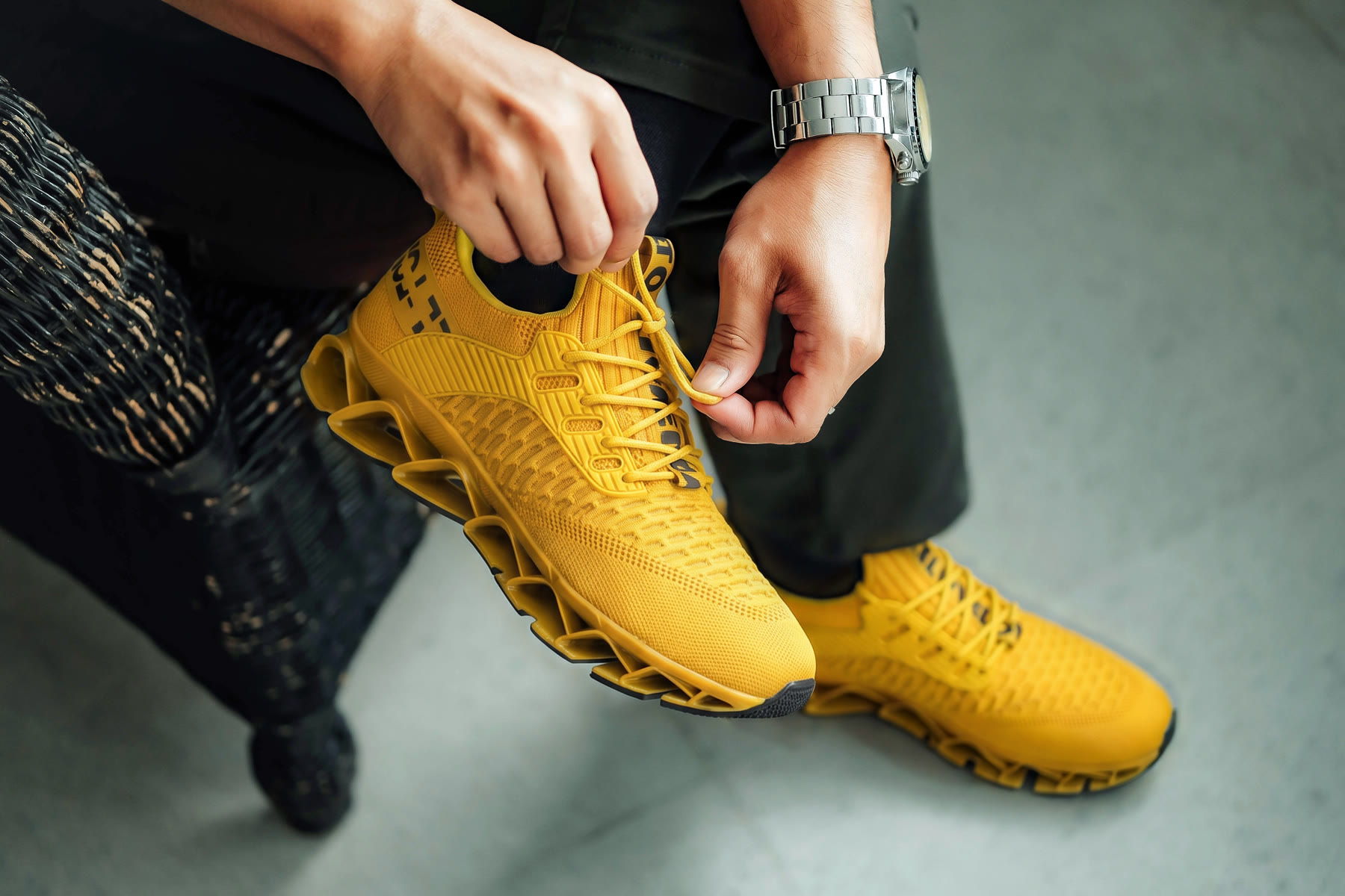 Close-up of the yellow shoe: knit upper, blade sole, and lettering